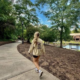 a person walking on a path between trees neat a body of water