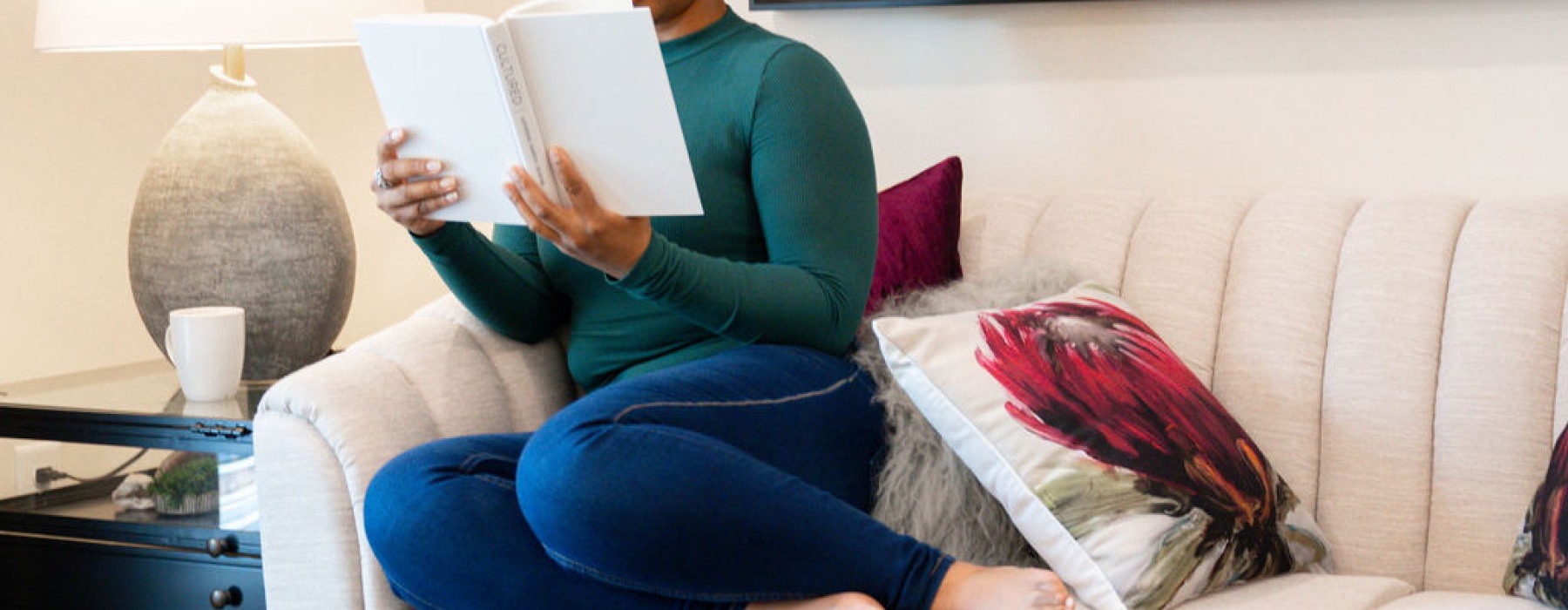 girl reading a book on a sofa in her apartment